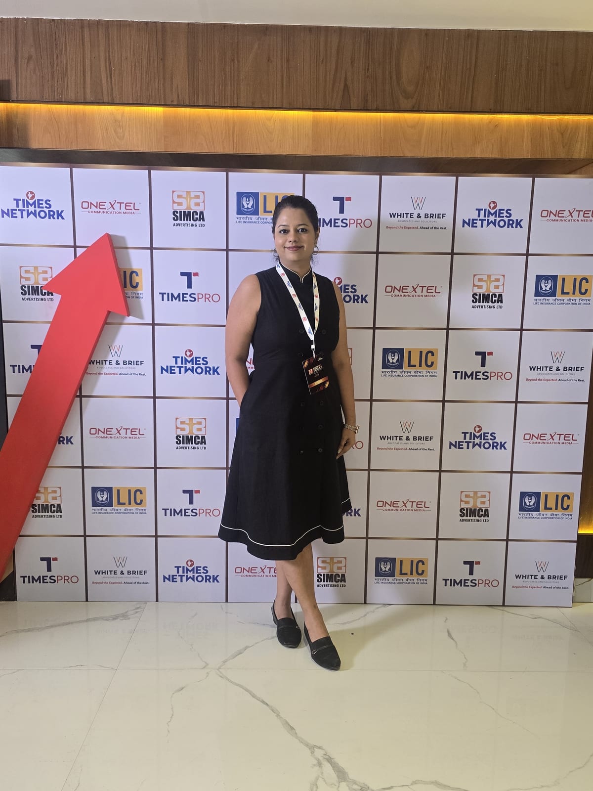 Shivani Tikadia seated with the trophy in front of The Big Call backdrop, alongside a SecComply colleague