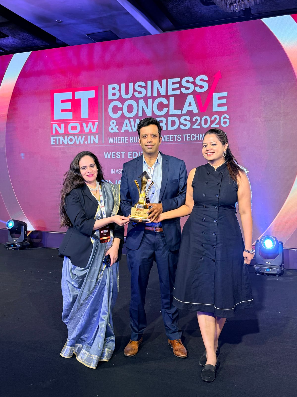 Shivani Tikadia receiving the trophy on stage with two presenters, ETNOW.in Business Conclave and Awards 2026, West Edition, Mumbai